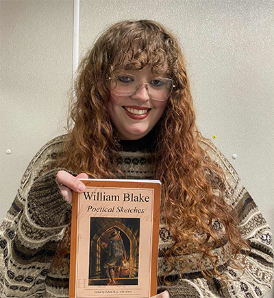 Student editor Janelle Brunette holding the book Poetical Sketches by William Blake